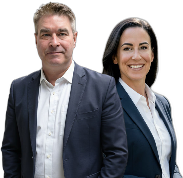 Two professionally dressed adults, one man and one woman, standing side by side and smiling, both wearing dark suits and white shirts against a plain background.