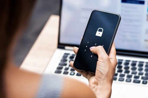 person holding smartphone displaying padlock icon and numeric passcode screen
