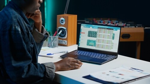 professional reviewing statistics and data dashboard on open laptop at desk